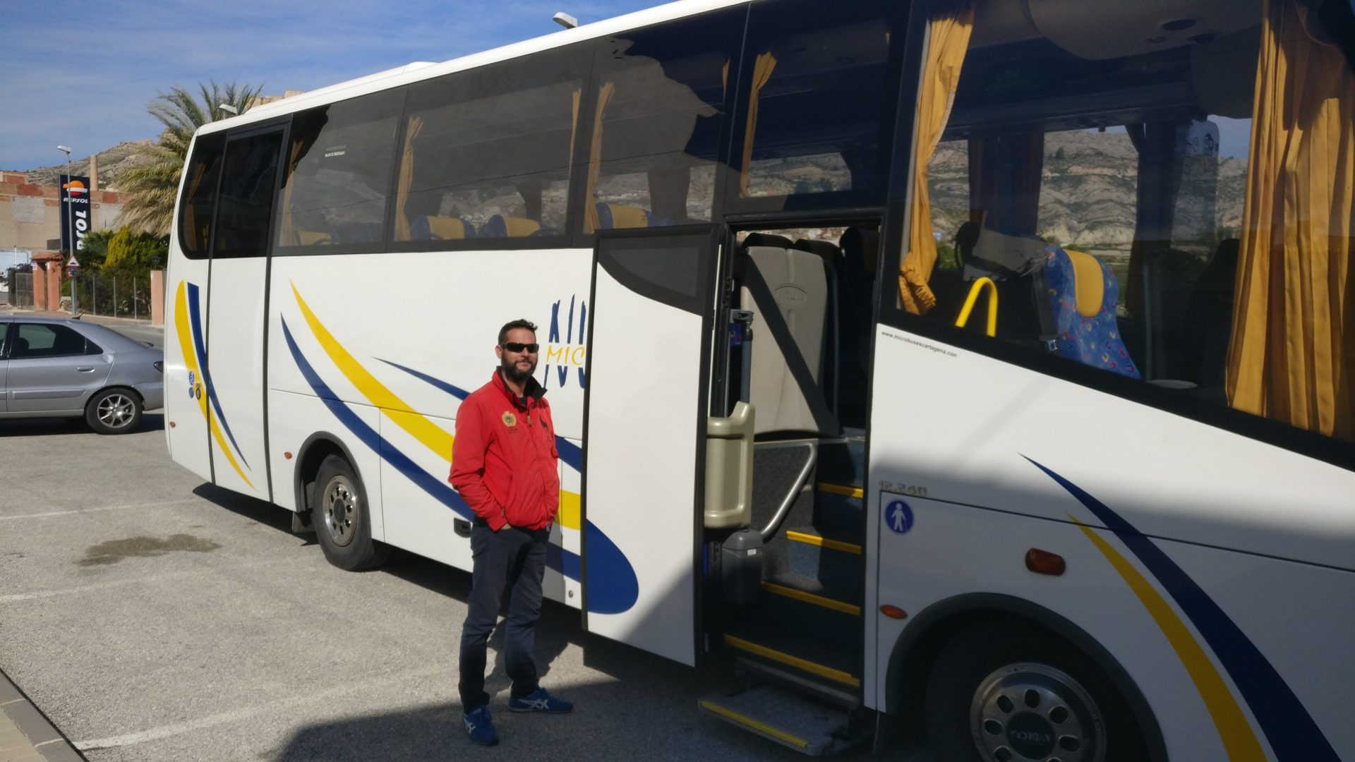 Autocar de Microbuses Núñez aparcado con la puerta delantera abierta y el conductor junto a ella